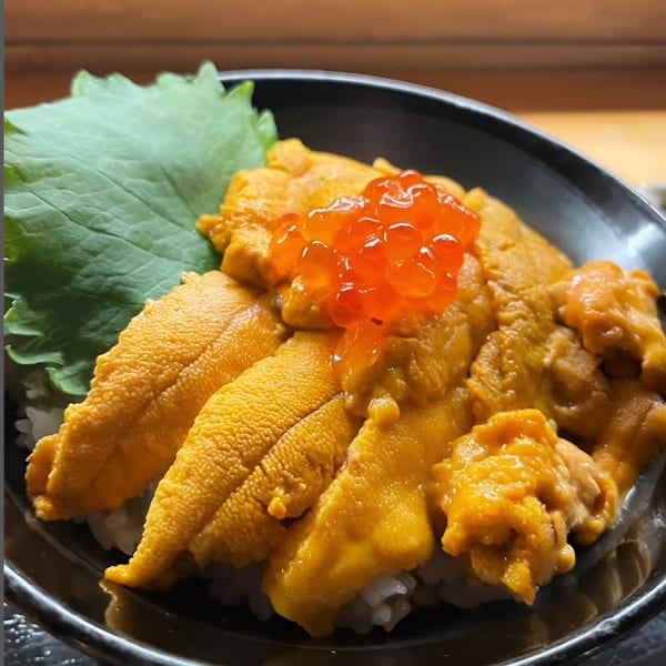 A close-up of a Japanese uni donburi bowl with bright orange sea urchin and salmon roe.