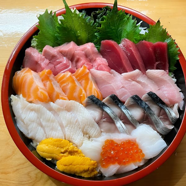 A vibrant chirashi bowl with various sashimi, including tuna, salmon, uni, and ikura, on rice.