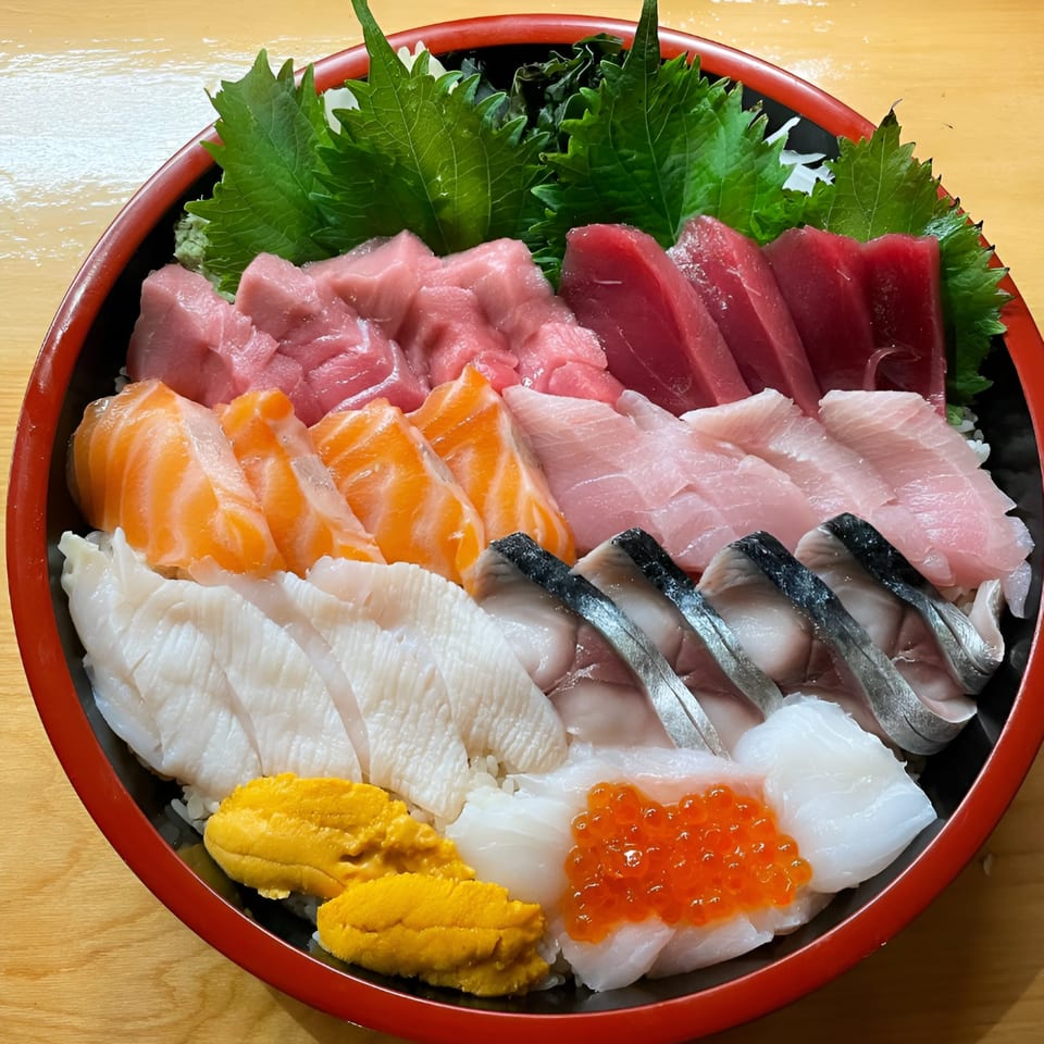A vibrant chirashi bowl with various sashimi, including tuna, salmon, uni, and ikura, on rice.